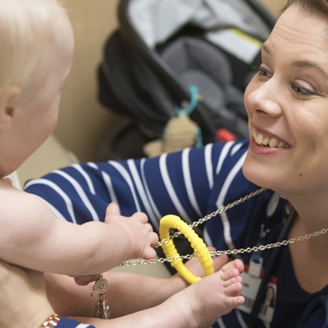 Smiling doctor reaches out to young boy patient in the movement disorders clinic