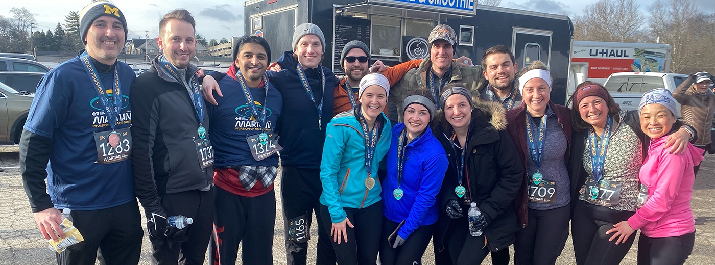  A group of individuals smiling and posing together for a photo at a race, celebrating community and wellness initiatives.