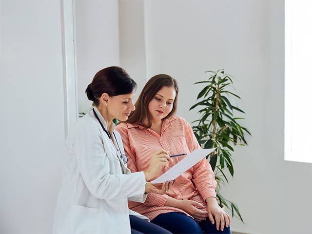 Woman in a pink shirt sits next to a nutrition counselor as they discuss treatment plans