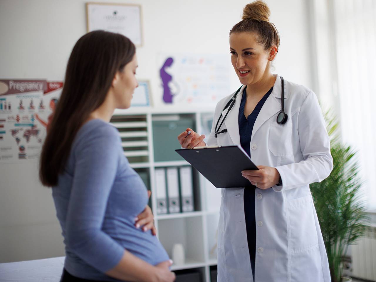 A doctor and a pregnant woman engage in a conversation about her prenatal care.