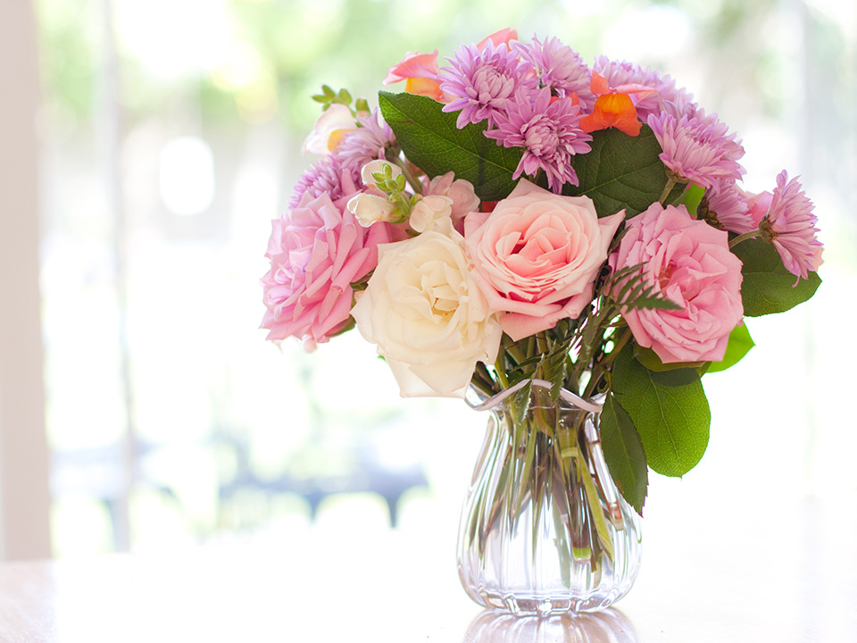 Pink and purple flowers in a vase sitting on a hospital table