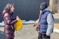 A woman in a winter coat converses with a man in a hoodie, highlighting community engagement in CPR training initiatives.