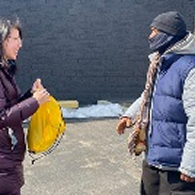 A woman in a winter coat converses with a man in a hoodie, highlighting community engagement in CPR training initiatives.