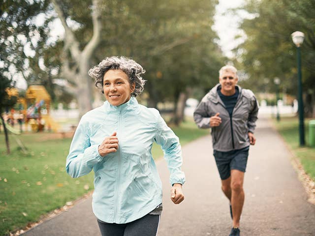 Older man and woman jog together in a park