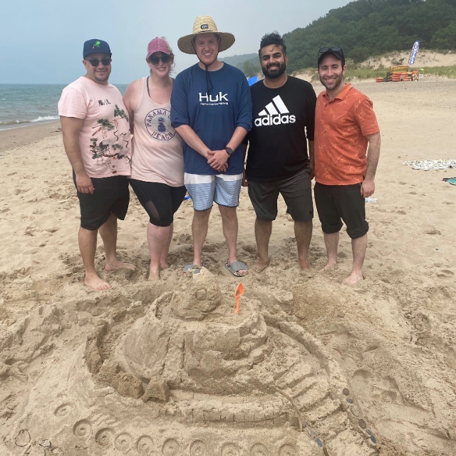 resident at the beach posing by the sandcastle they built
