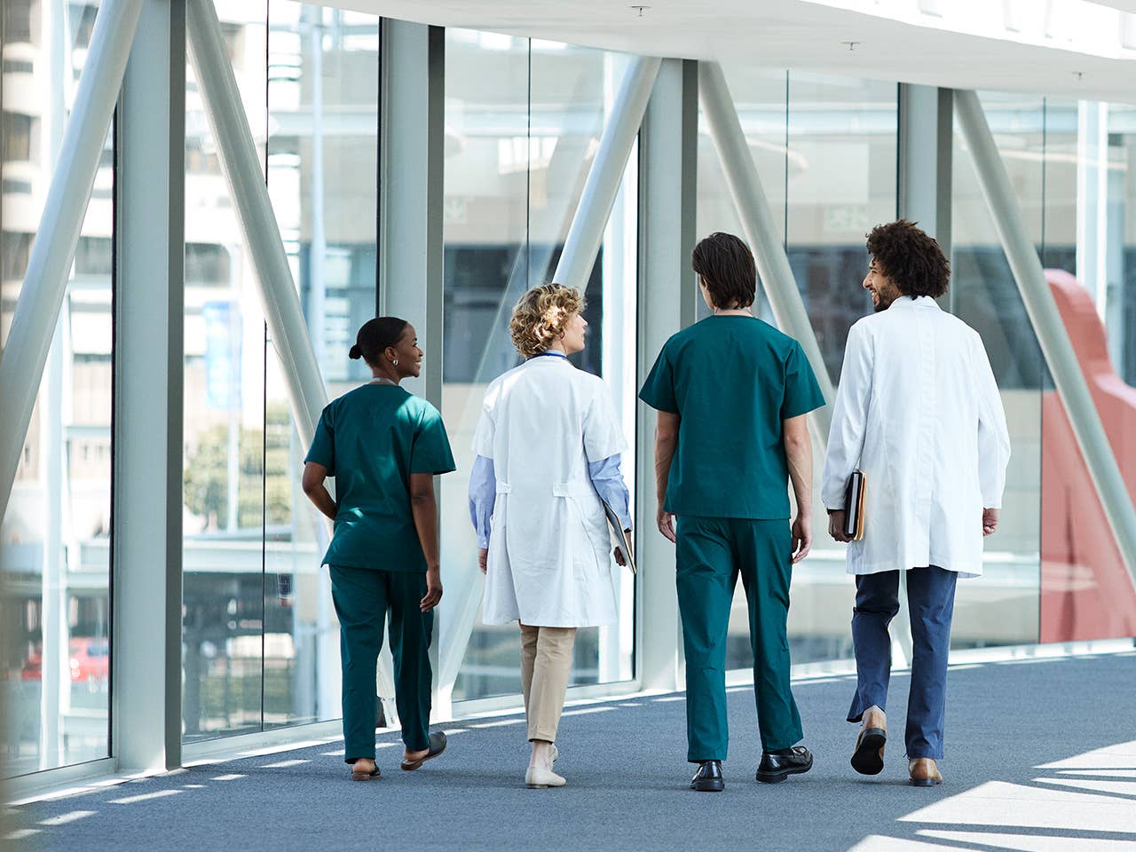 Three doctors walking together in a hallway, representing teamwork in clinical research and the pursuit of healing.