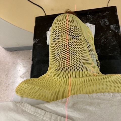 A person lies on a table preparing for proton beam arc therapy.