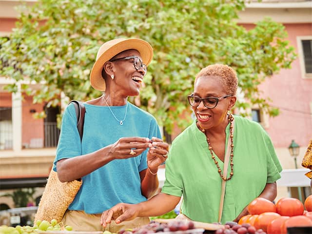 People selecting fresh fruits and vegetables at an outdoor market, supporting Food Wellness through healthy eating choices.