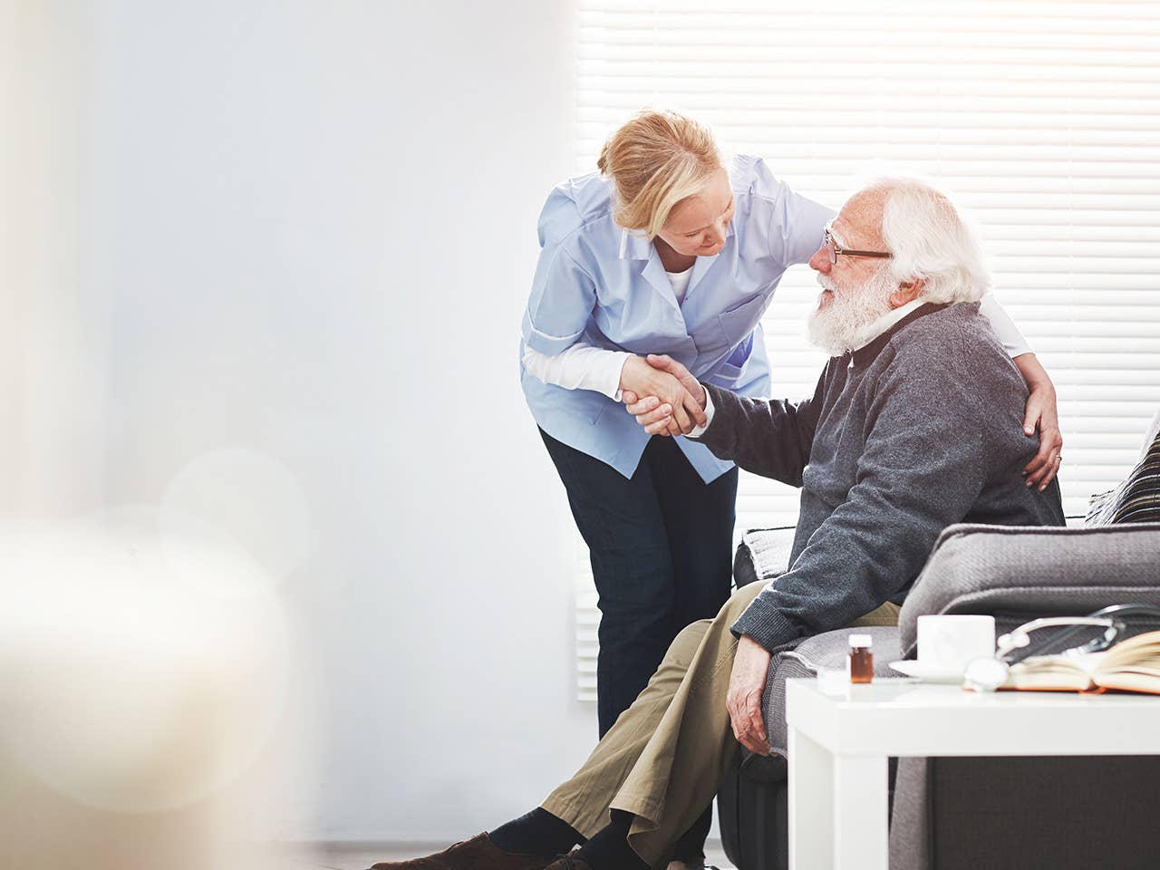 Corewell Health palliative care team member leans over next to an elderly male patient as he sits in a chair
