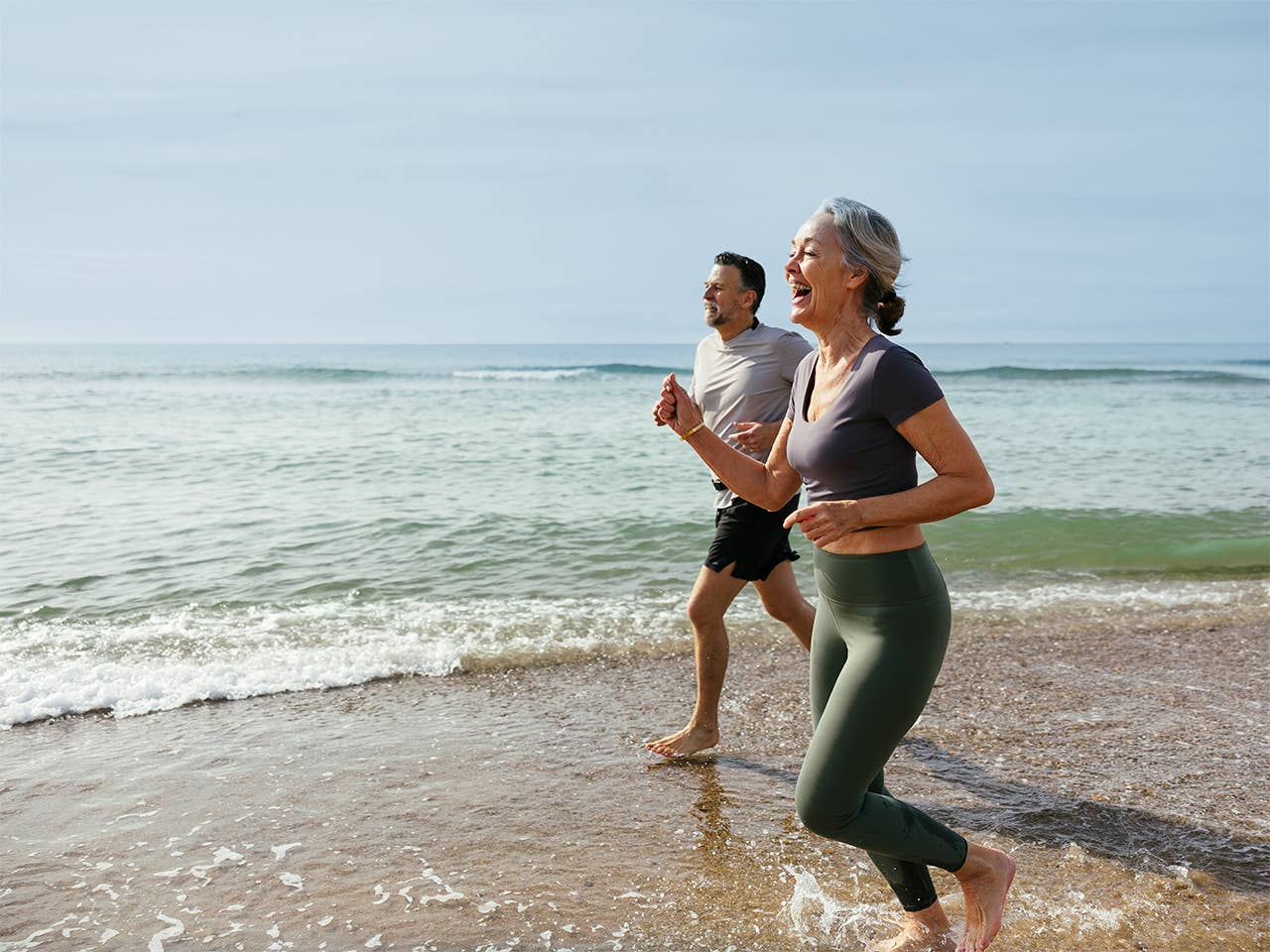 Man and woman running side-by-side on beach