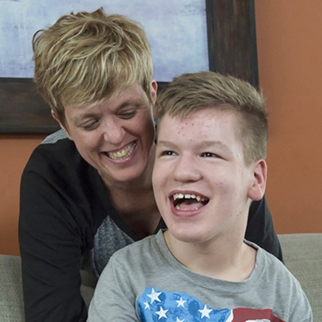 Smiling preteen boy sits with his smiling mother