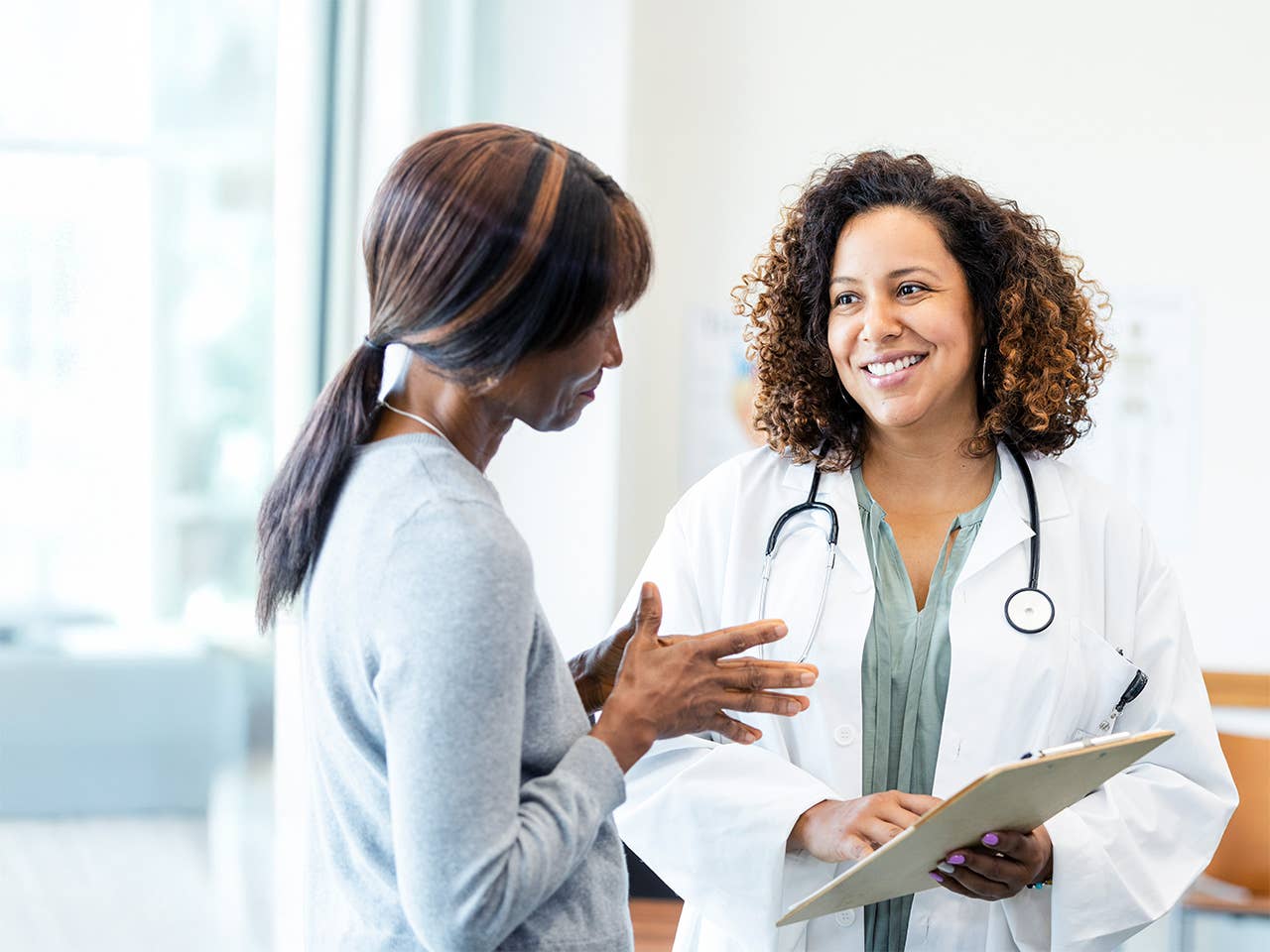 A woman engaged in conversation with a doctor inside a medical office.