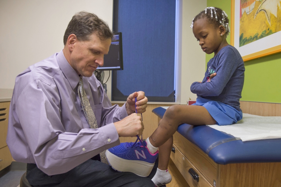 Doctor ties a shoe for a girl in the pediatric orthopedics clinic