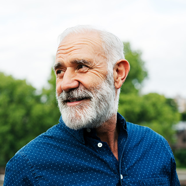 Old male standing outside looking in the other direction