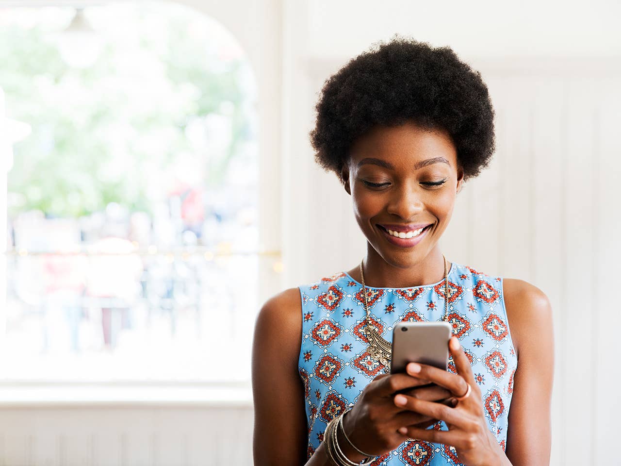 women smiling while holding her phone scheduling a doctors appointment