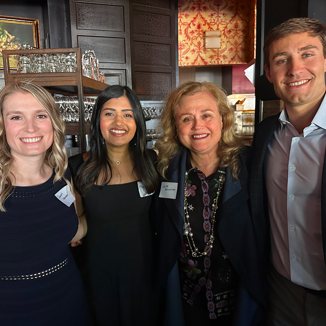 Four attendees posing together for a photo during a residency celebration dinner