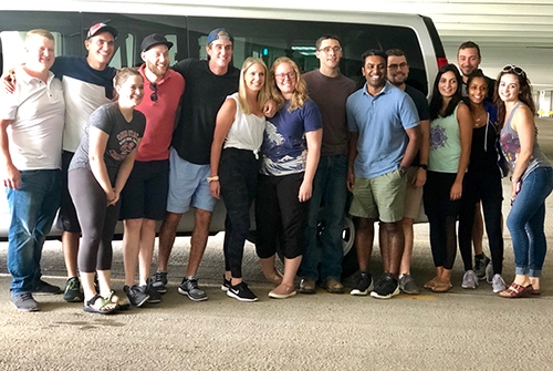 A group of individuals gathered in front of a van, ready for a resident outing, showcasing camaraderie and excitement.