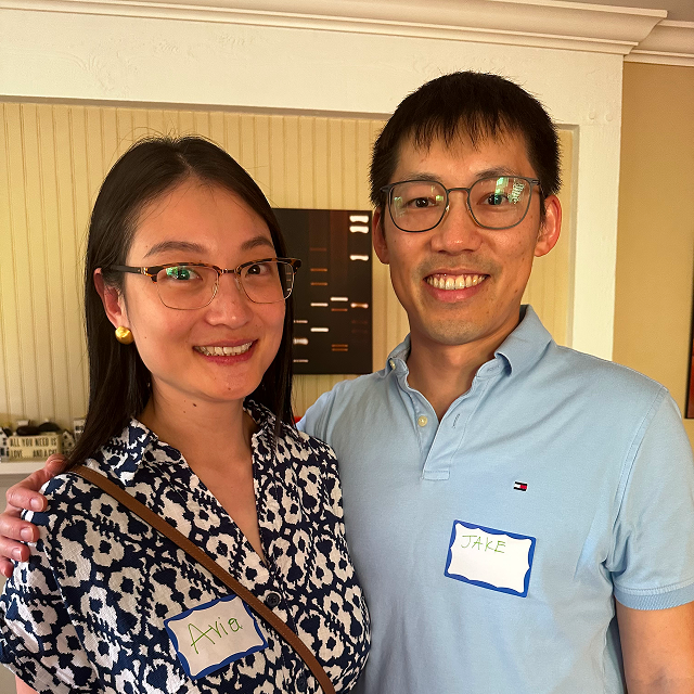 Two attendees wearing name tags pose together indoors at a community gathering.