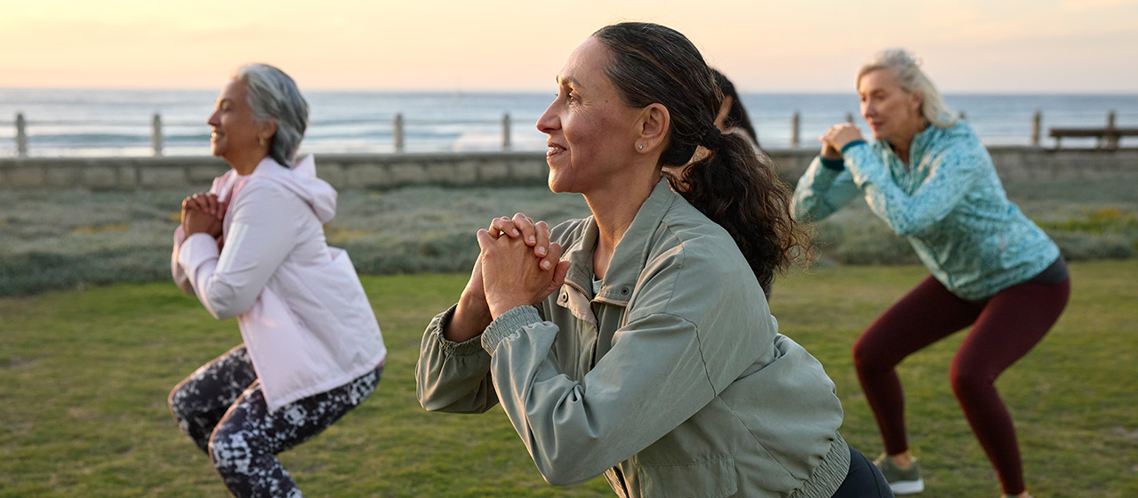 People performing outdoor squats near the beach, highlighting exercise, mobility, and activities linked to hip pain causes and treatment.