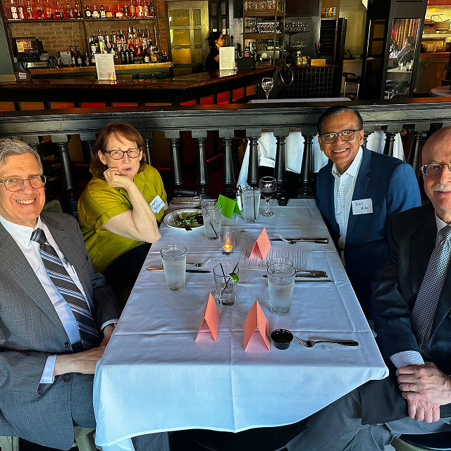 Four attendees seated together at a restaurant table during a residency celebration dinner