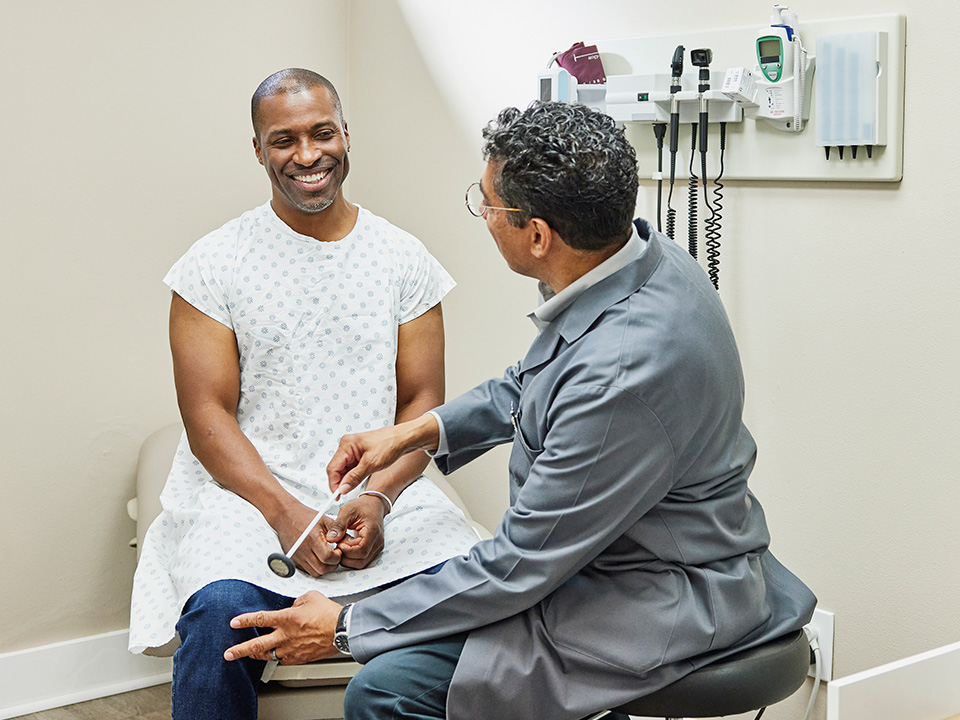 Patient discussing knee pain with a doctor during a medical exam in a clinic treatment room.