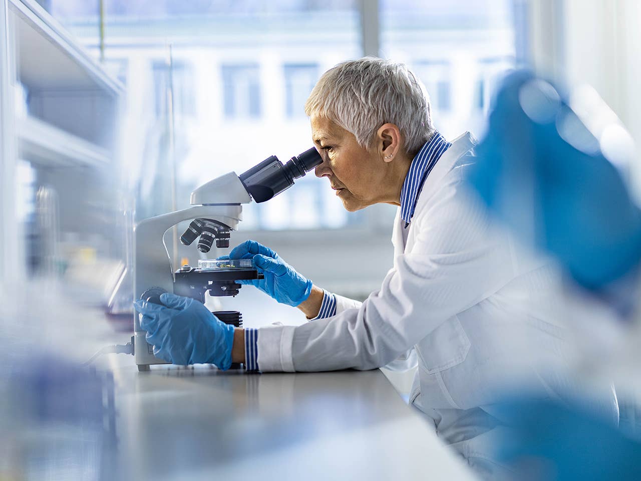 Female doctor in white lab coat looks into a microscope