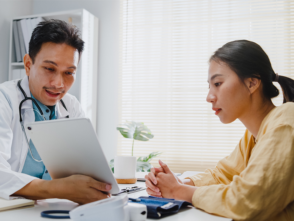 A doctor is discussing health concerns with a patient in a clinical setting.