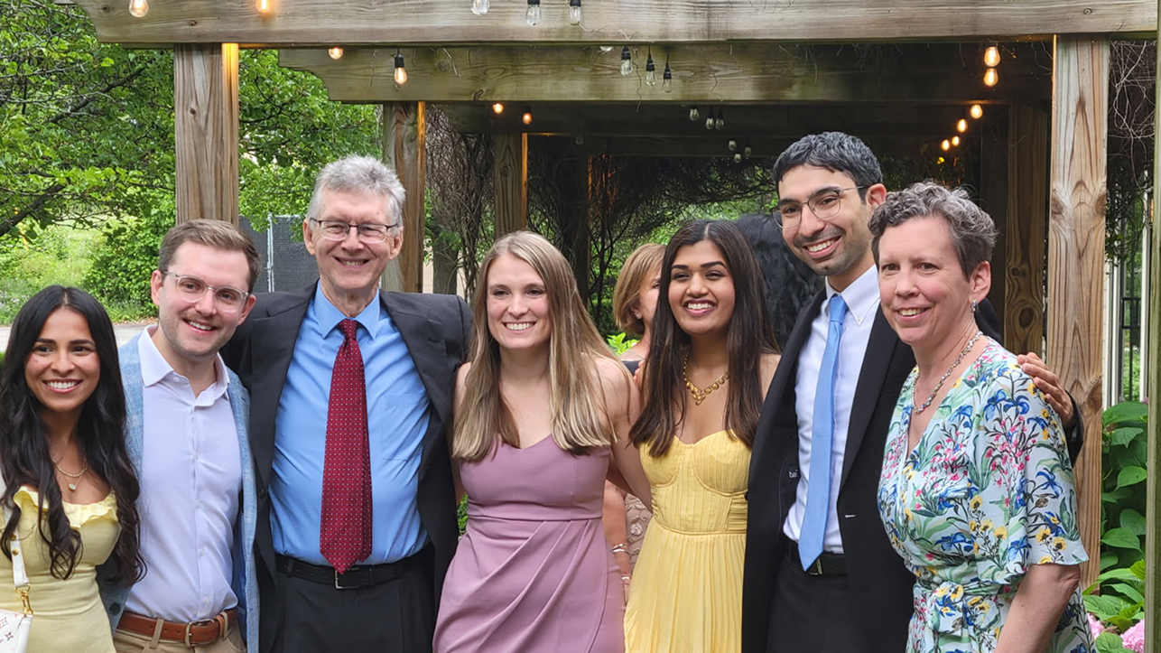 Group photo of wedding guests gathered under a pergola with string lights at alumnus Jordan Jabara’s wedding.