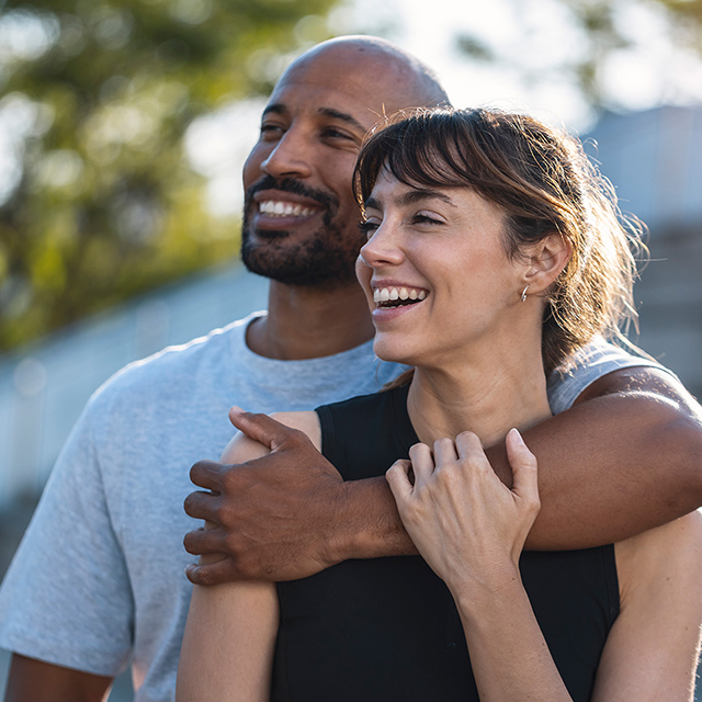 A man and woman smile warmly while embracing each other in a joyful moment.
