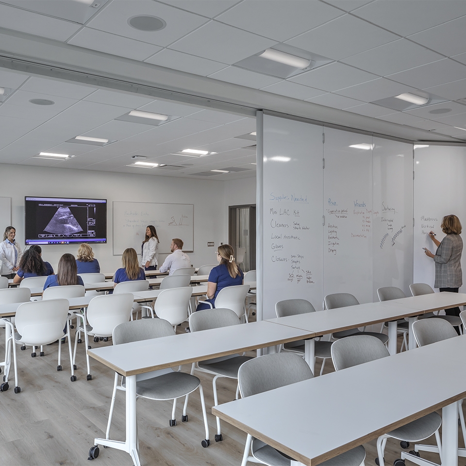 A bright room featuring whiteboards and tables arranged for collaborative work or meetings.