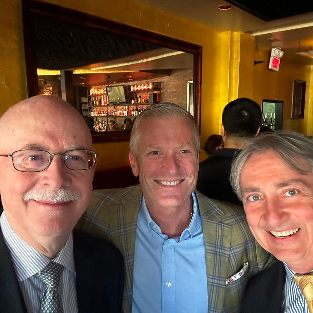 Three attendees posing together for a group photo during a residency celebration dinner