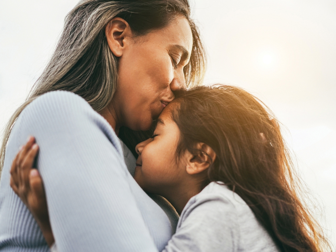 A mother kissing her daughter