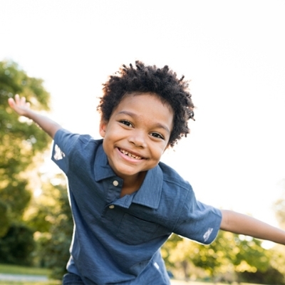 Smiling Black boy in a blue shirt in the sunlight