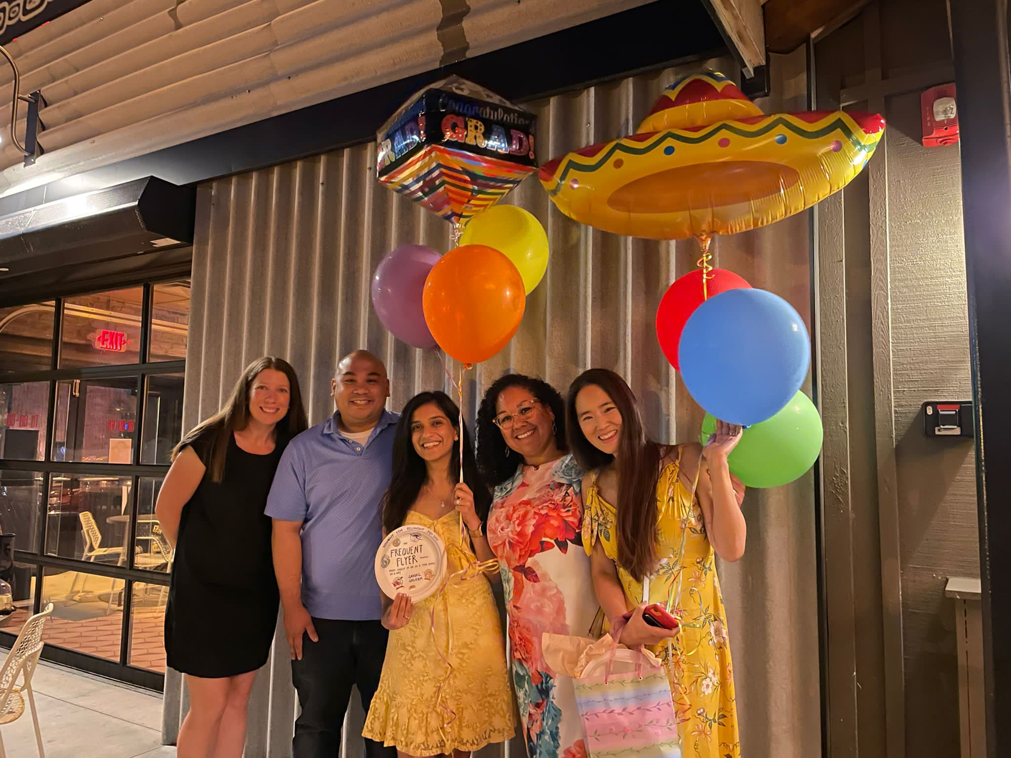 A group of individuals joyfully posing for a photo, surrounded by colorful balloons, celebrating wellness and camaraderie.