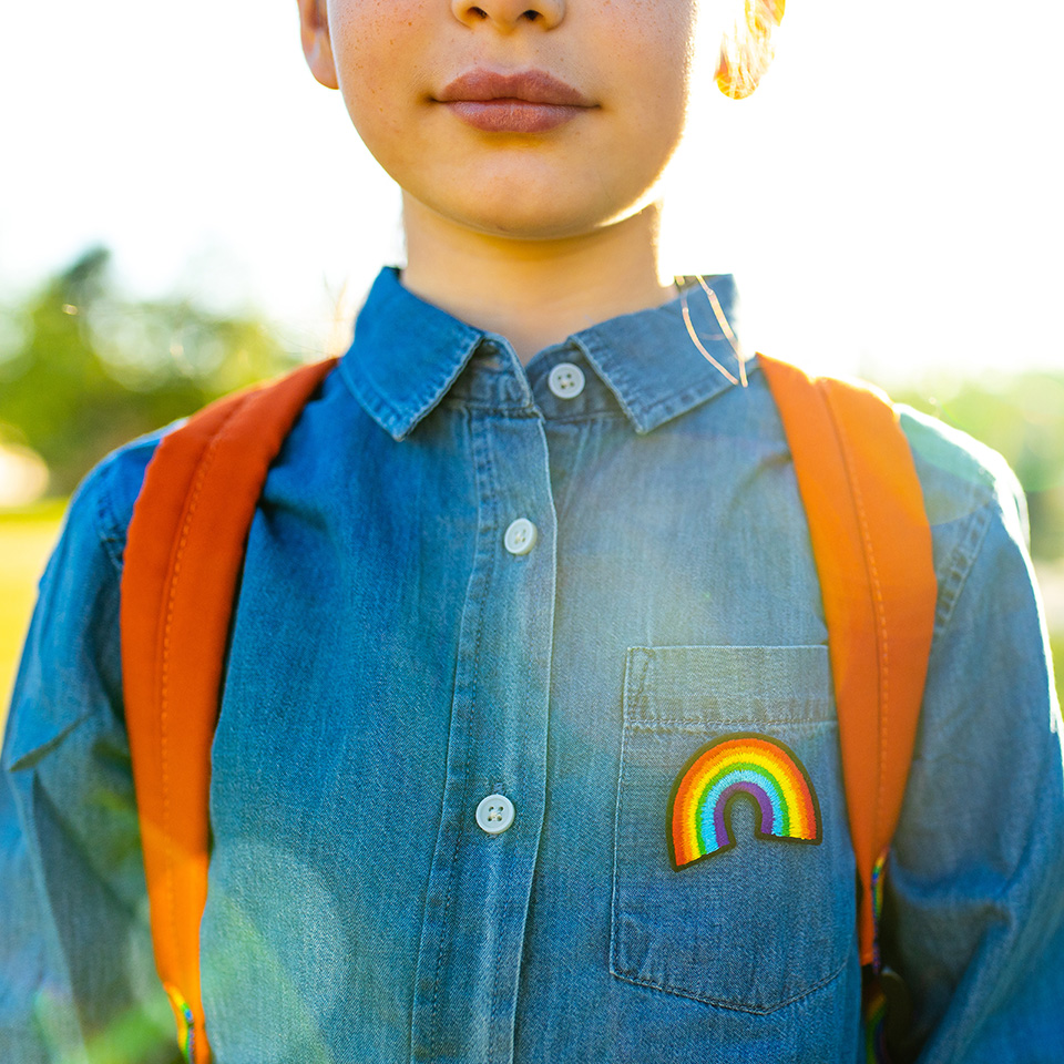Boy in button-up denim shirt with a rainbow on the chest