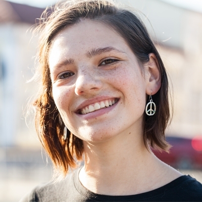 Smiling teenage girl with brown hair and freckles in the sunshine