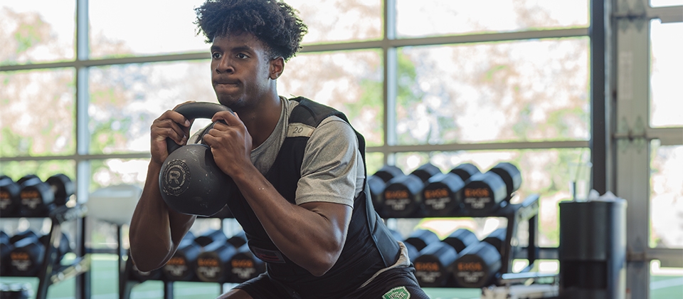 A man performs a kettlebell lift in a gym, showcasing strength and focus during his workout session.