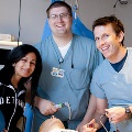 Three medical residents in scrubs smiling for a photo, showcasing their camaraderie and dedication to healthcare.