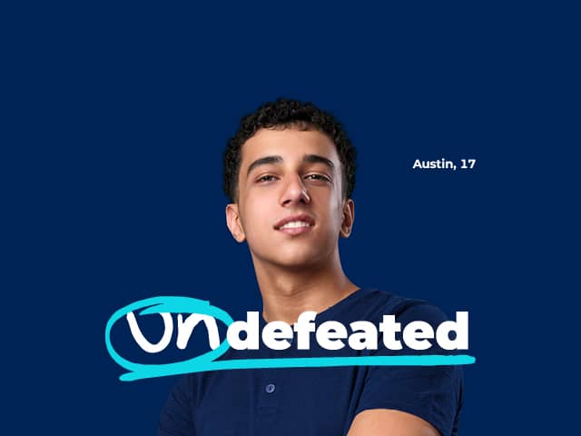 Preteen girl in a dark blue sweater standing with arms folded in front of dark blue background