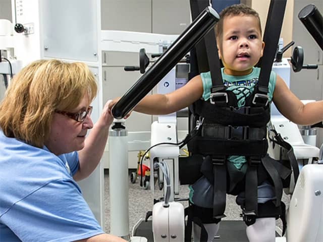 Little boy working through exercises at rehab facility with a medical professional.