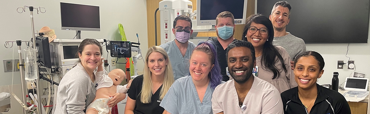 A group of individuals collaborates in a hospital room, engaged in a medical simulation training session.