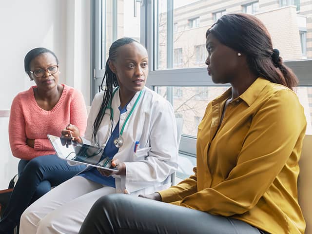 Three women converse with a doctor, focusing on medical concerns and personal health discussions.