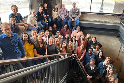 A diverse group of individuals gathered on the stairs of a building, enjoying a moment during a resident outing.