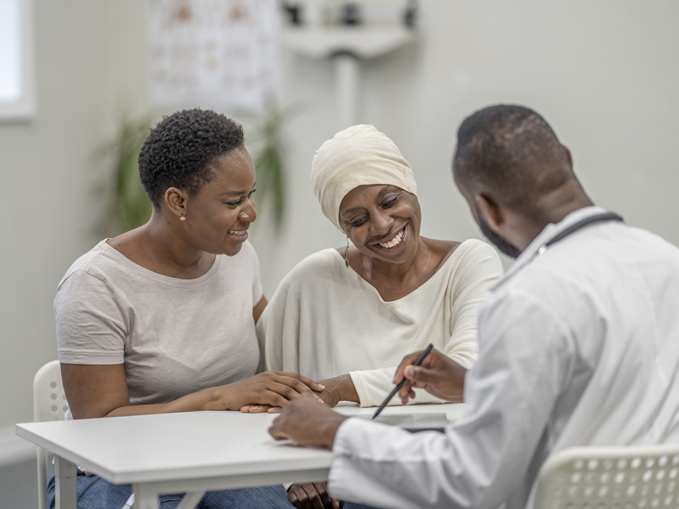 A woman and a man consult with a doctor in a medical office, discussing health concerns.