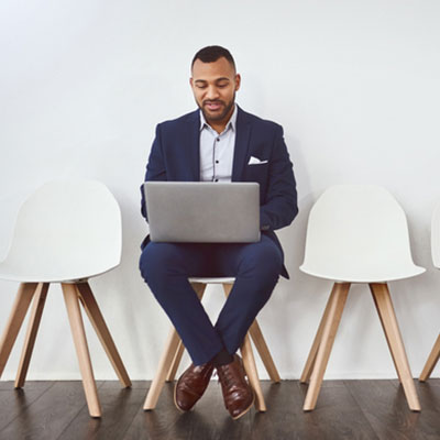 Black man in a suit sitting with a laptop