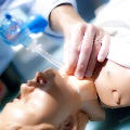 A person is inserting an oxygen tube into a medical dummy, demonstrating a life-saving procedure for training purposes.
