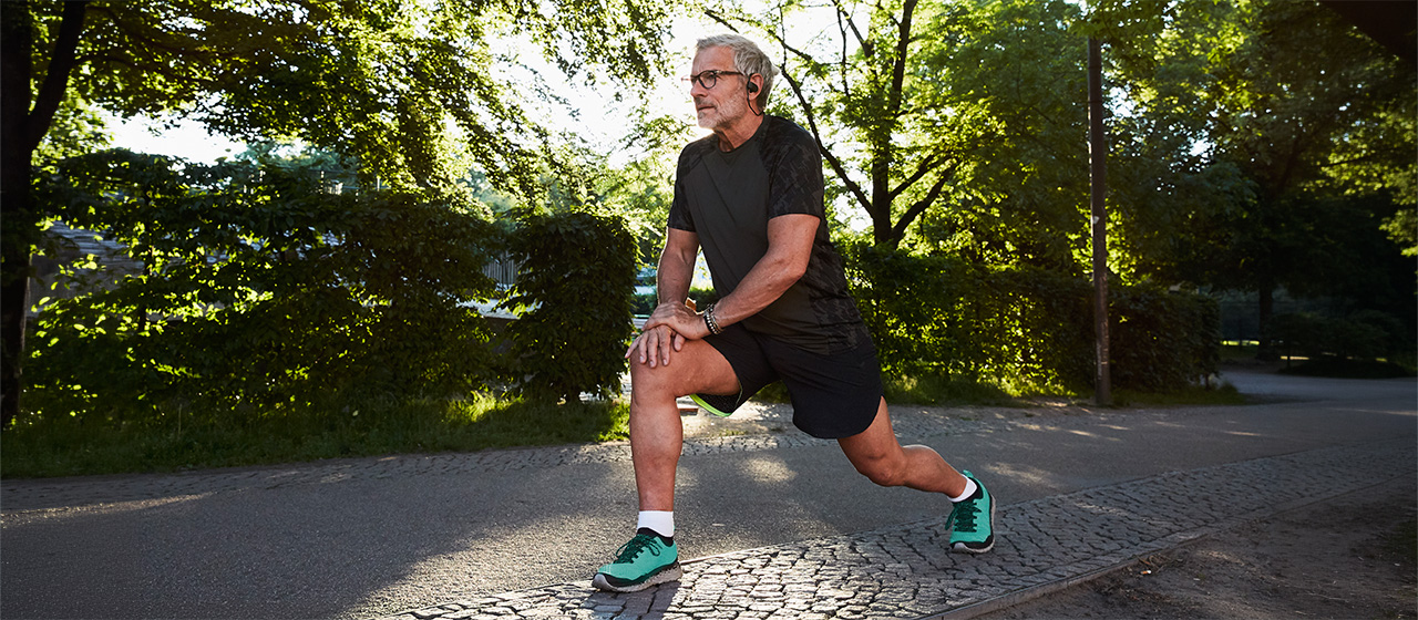 Person stretching outdoors before exercise, highlighting activities and movement that can contribute to knee pain.