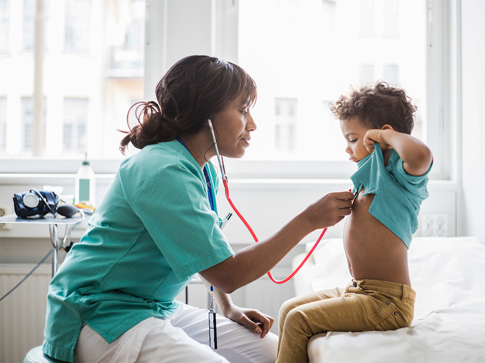 Femail medical provider is talking to and checking out a small child during an appointment