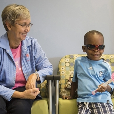 Young Black boy and caregiver sitting in chairs in waiting room