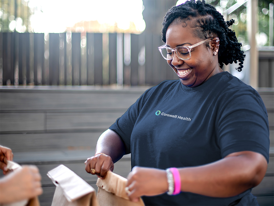 A woman in a blue shirt hands a bag to another woman, both engaged in a friendly exchange.